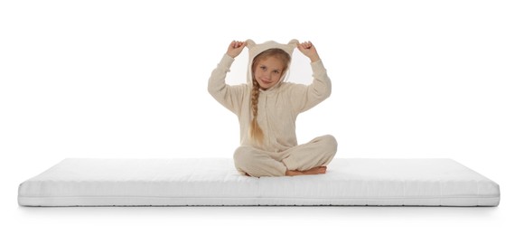 Little girl sitting on mattress against white background
