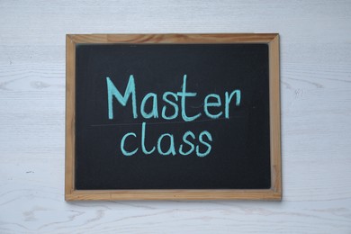 Photo of Blackboard with phrase Master class on white wooden table, top view