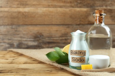 Photo of Bamboo toothbrush and jar of baking soda on wooden table, space for text