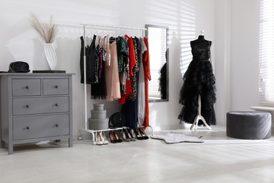 Photo of Rack with collection of beautiful festive clothes in stylish room interior