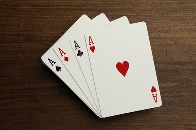 Photo of Four aces playing cards on wooden table, top view. Poker game