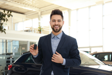 Salesman with key in modern car salon
