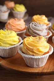 Photo of Tasty cupcakes with cream on wooden stand, closeup