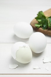 Boiled eggs and pieces of shell on white wooden table