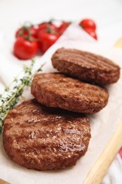 Wooden board with tasty grilled hamburger patties on table, closeup