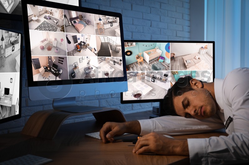 Photo of Male security guard sleeping near monitors at workplace