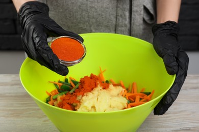 Photo of Woman preparing spicy cabbage kimchi at wooden table, closeup