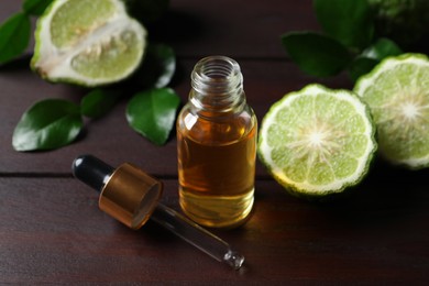 Bottle of essential oil, pipette and fresh bergamot fruits on wooden table