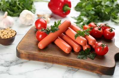 Fresh raw vegetarian sausages with parsley, tomatoes and soybeans on white marble table