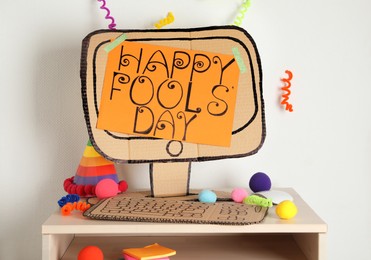 Fake computer with words Happy Fool's Day and party accessories on table