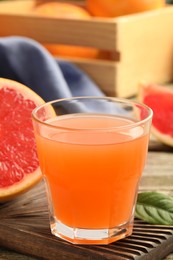 Glass of delicious grapefruit juice on wooden table