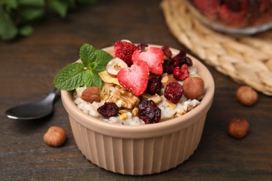Photo of Oatmeal with freeze dried fruits, nuts and mint on wooden table, closeup