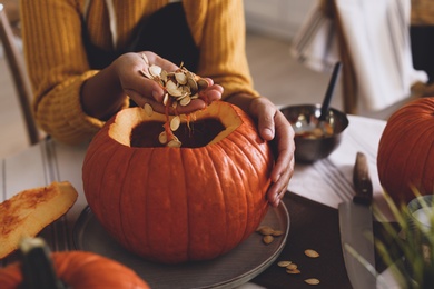 Woman making pumpkin jack o'lantern at table, closeup. Halloween celebration