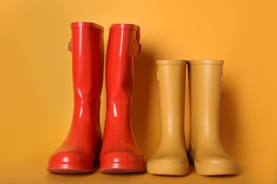 Two pairs of rubber boots on orange background