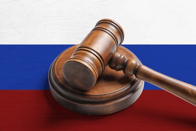 Judge's gavel on wooden background in color of Russian flag. Concept of sanctions against Russia
