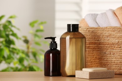 Photo of Solid shampoo bar and bottles of cosmetic product on wooden table in bathroom