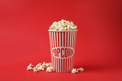 Delicious popcorn in paper cup on red background