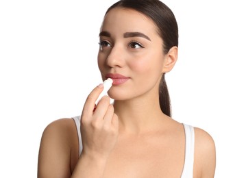Young woman applying lip balm on white background