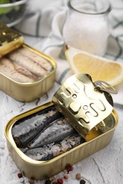 Photo of Open tin cans with mackerel fillets on light textured background