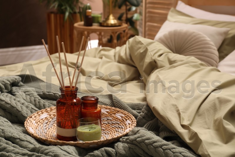 Reed freshener and candles on bed indoors