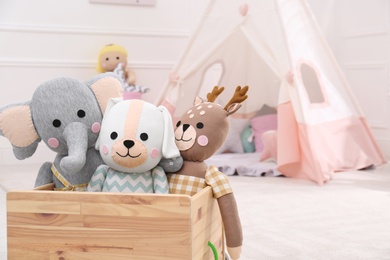 Wooden crate with cute toys in stylish playroom, space for text. Interior design