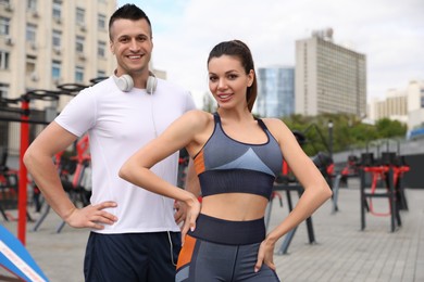 Woman and man in fitness clothes near outdoor gym