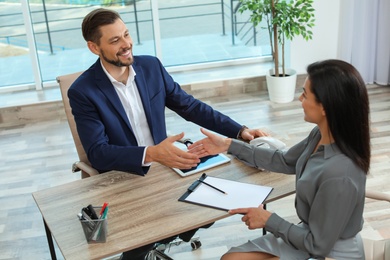 Photo of Human resources manager shaking hands with applicant during job interview in office