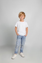 Cute little boy in casual outfit on light grey background