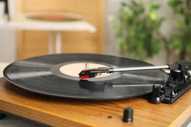 Turntable with vinyl record on blurred background, closeup. Space for text