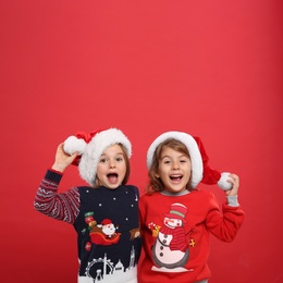 Kids in Christmas sweaters and Santa hats on red background