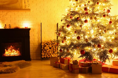 Photo of Beautiful Christmas tree and gifts near fireplace in room. Interior design