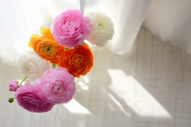 Bouquet of beautiful ranunculus flowers near window on floor, top view. Space for text