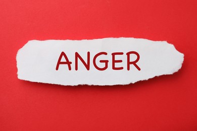 Photo of Piece of paper with word Anger on red background, top view