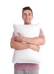 Young man in pajamas embracing pillow on white background