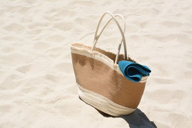 Soft blue towel in beach bag on sand