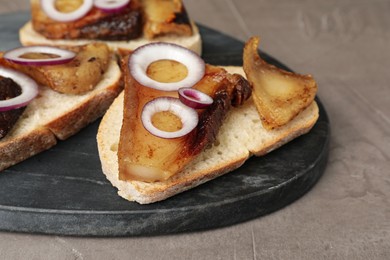 Photo of Tasty fried pork lard with bread slices and onion on grey table, closeup