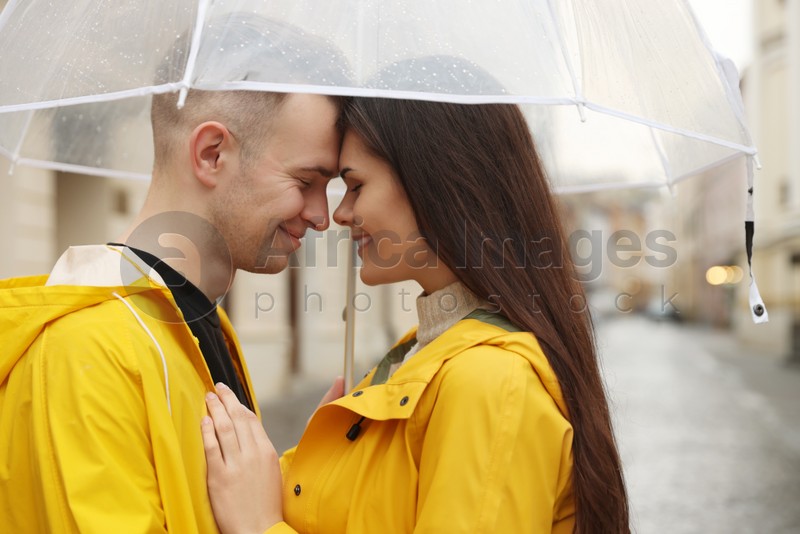 Lovely young couple with umbrella on city street