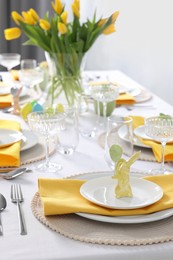 Photo of Festive table setting with glasses and vase of tulips. Easter celebration