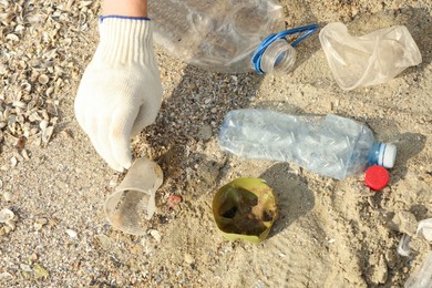 Woman in gloves collecting garbage on beach, above view