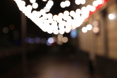 Photo of Beautiful view of night city street decorated with garlands. Bokeh effect