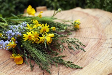 Photo of Bouquet of beautiful wildflowers on wooden stump outdoors, closeup