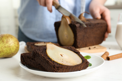 Slices of tasty pear bread and blurred view of woman with knife on background