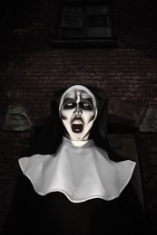 Photo of Portrait of scary devilish nun outdoors. Halloween party look