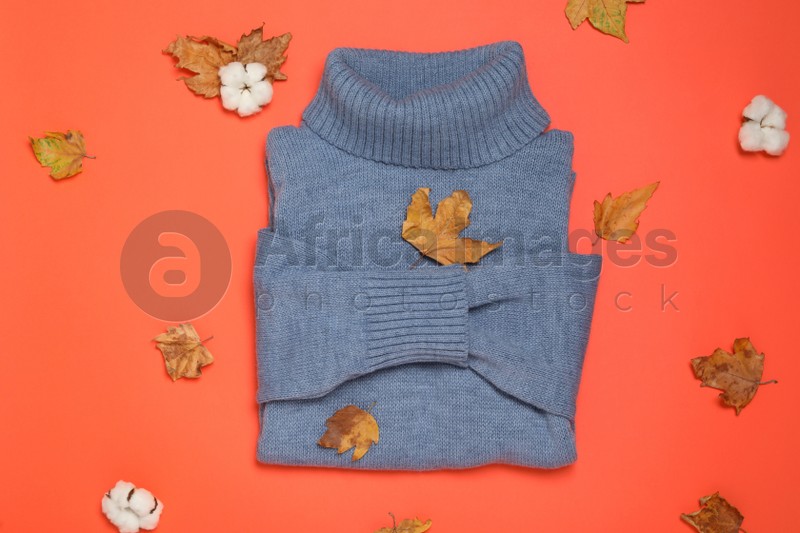 Photo of Warm sweater, dry leaves and cotton flowers on orange background, flat lay. Autumn season