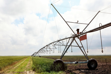 Modern irrigation system in field under cloudy sky. Agricultural equipment