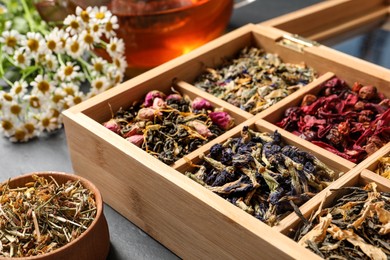 Different dry teas and chamomile flowers on table, closeup