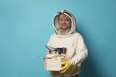 Beekeeper in uniform with tools on light blue background