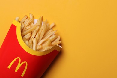 MYKOLAIV, UKRAINE - AUGUST 12, 2021: Big portion of McDonald's French fries on orange background, top view. Space for text