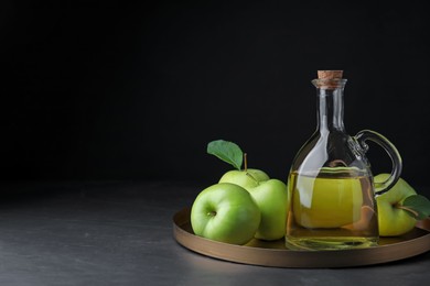 Photo of Fresh ripe green apples and jug of tasty juice on black table, space for text