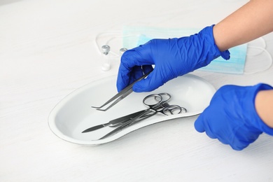 Doctor in sterile gloves with medical tools at table